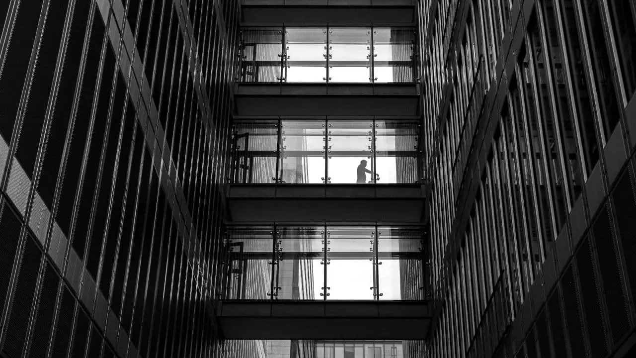 A black and white photo of a person standing in an atrium.