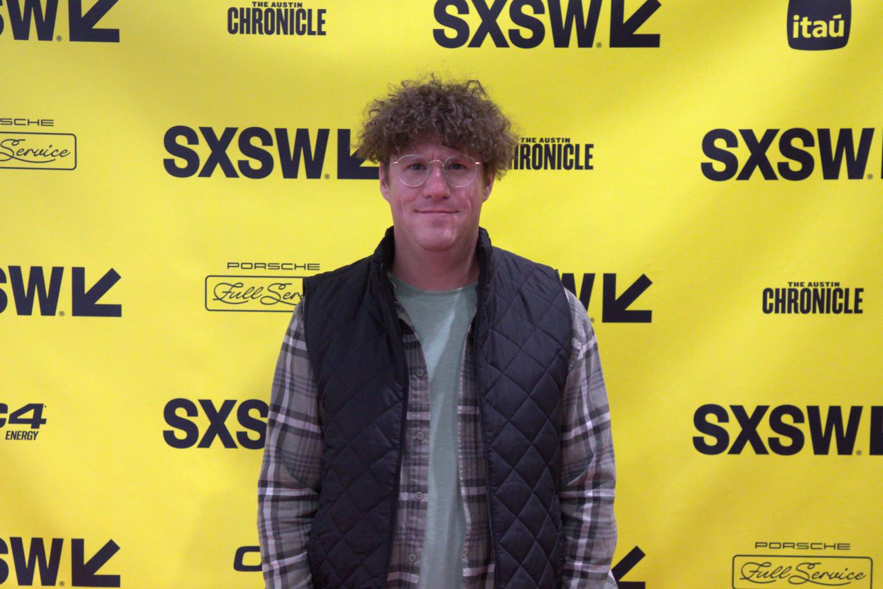 A man standing in front of a yellow wall at sxsw.